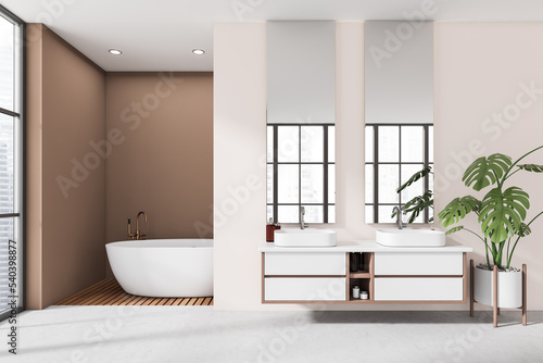 Light bathroom interior with double sink and tub with panoramic window