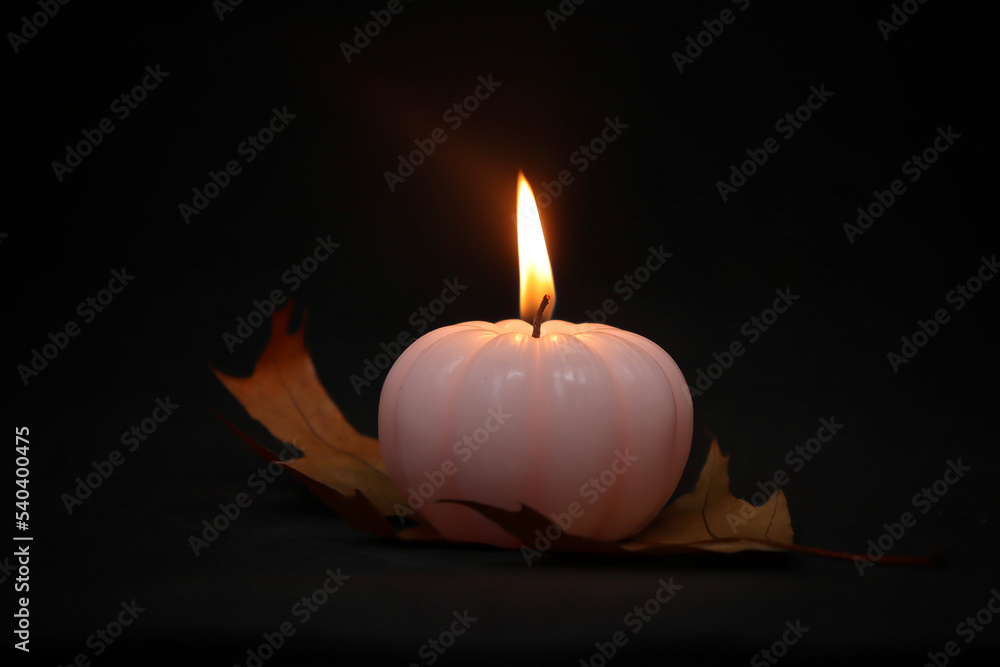 Candle in the form of a pumpkin on a black background