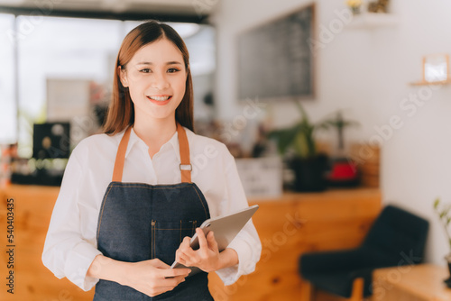 Opening a small business, AHappy Asian woman in an apron standing near a bar counter coffee shop, Small business owner, restaurant, barista, cafe, Online, SME, entrepreneur, and seller concept photo