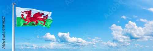 Wales flag waving on a blue sky in beautiful clouds - Horizontal banner photo