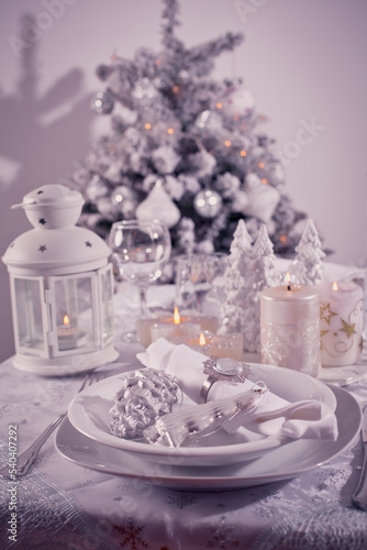 Festive  Christmas table place setting with silverware  candles and decorated Christmas tree