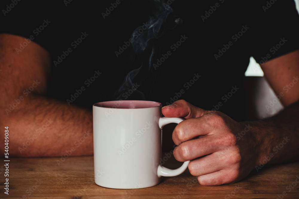 man holding steaming cup of coffee man holding steaming cup of coffee