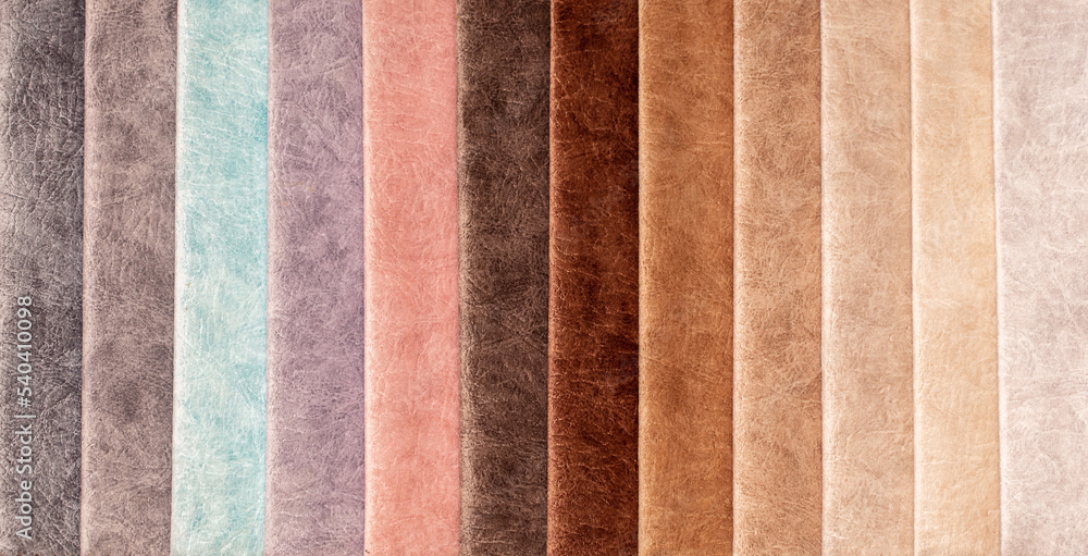 Fototapeta premium Fabric texture close up. Fabric swatches in different colors are stacked for selection. A variety of shades of upholstery material for furniture and interior. A set of multi-colored rolls of material.