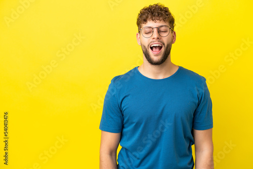 Young handsome caucasian man isolated on yellow background shouting to the front with mouth wide open