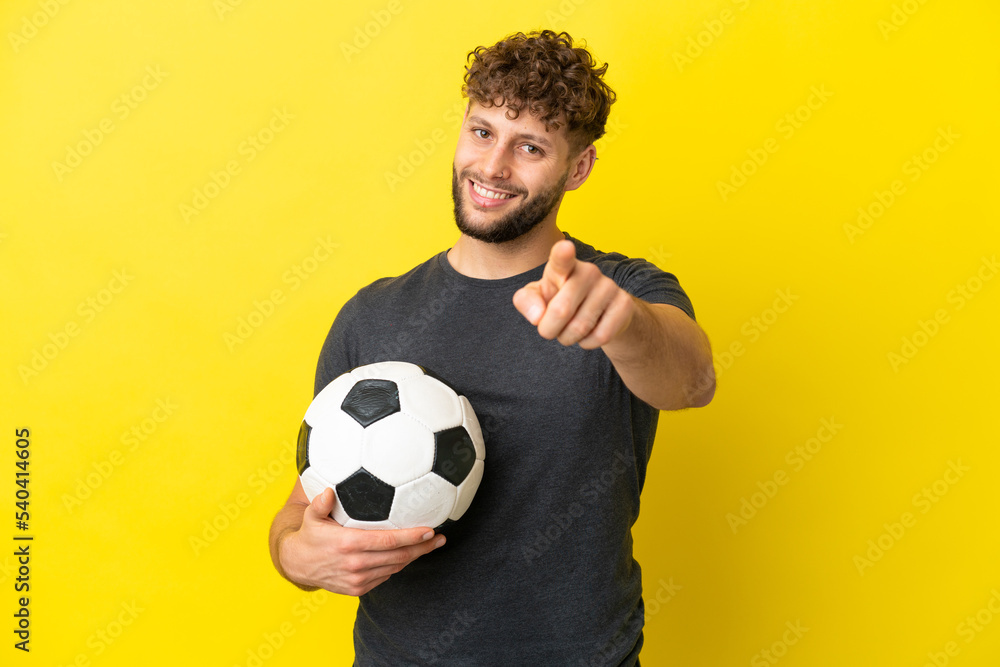 Handsome young football player man isolated on yellow background pointing front with happy expression Handsome young football player man isolated on yellow background pointing front with happy expression