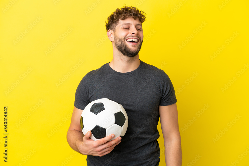 Handsome young football player man isolated on yellow background laughing