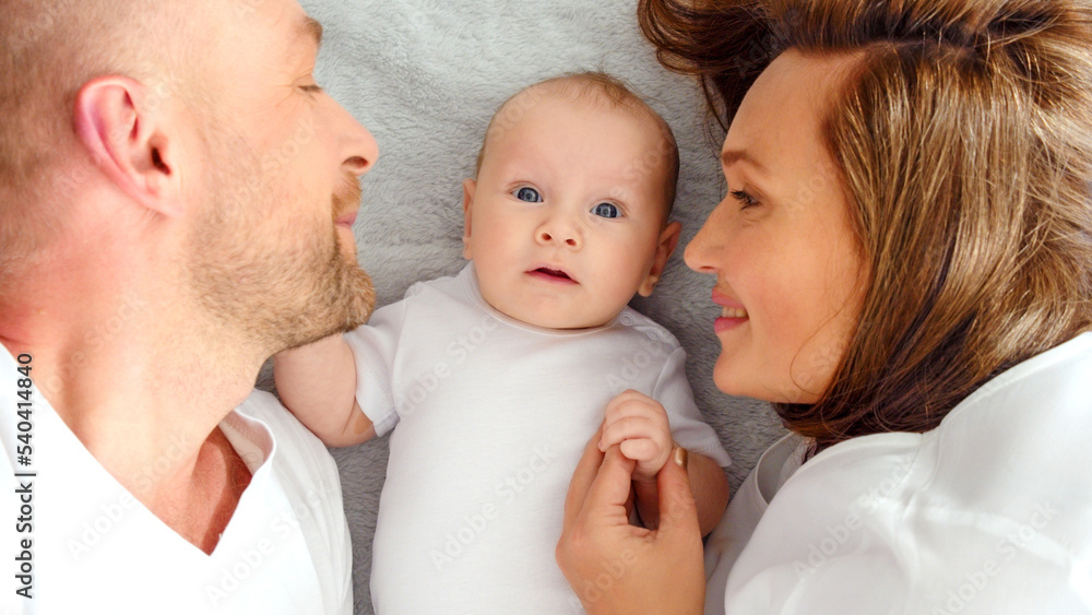 Happy parents with his newborn baby, top view. Happy family. Healthy newborn baby with mom and dad. Close up Faces of the mother, father and infant baby. Cute Infant boy and parents. Happy parents with his newborn baby, top view. Happy family. Healthy newborn baby with mom and dad. Close up Faces of the mother, father and infant baby. Cute Infant boy and parents.
