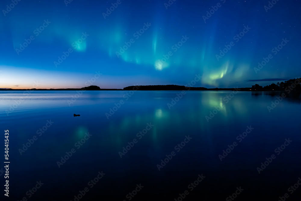 Northern lights dancing over calm lake in Farnebofjarden national park in north of Sweden