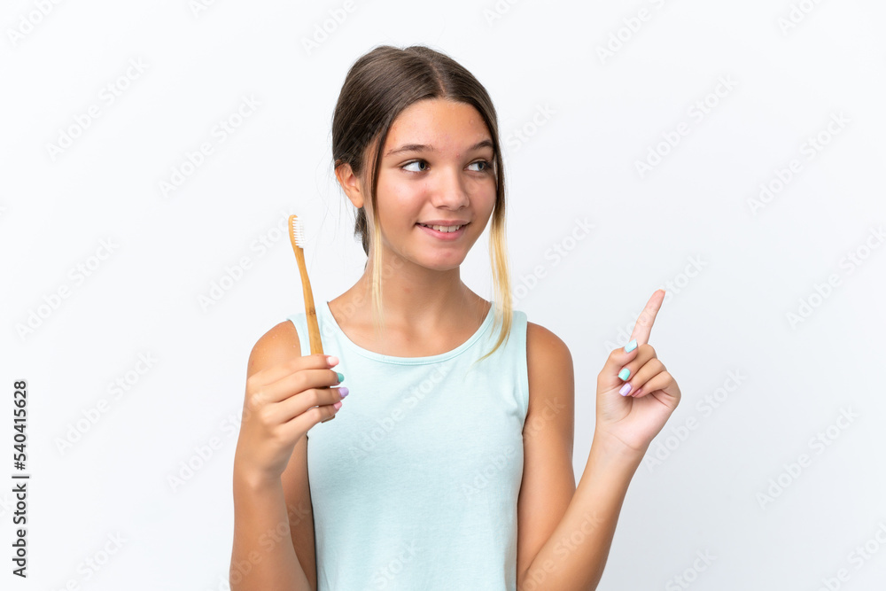 Little caucasian girl holding a toothbrush isolated on white background intending to realizes the solution while lifting a finger up Little caucasian girl holding a toothbrush isolated on white background intending to realizes the solution while lifting a finger up