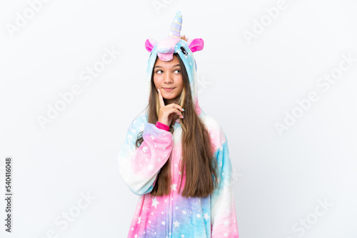 Little caucasian girl wearing unicorn pajama isolated on white background thinking an idea while looking up