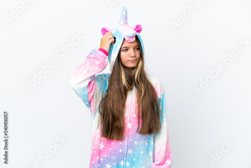 Little caucasian girl wearing unicorn pajama isolated on white background having doubts and with confuse face expression
