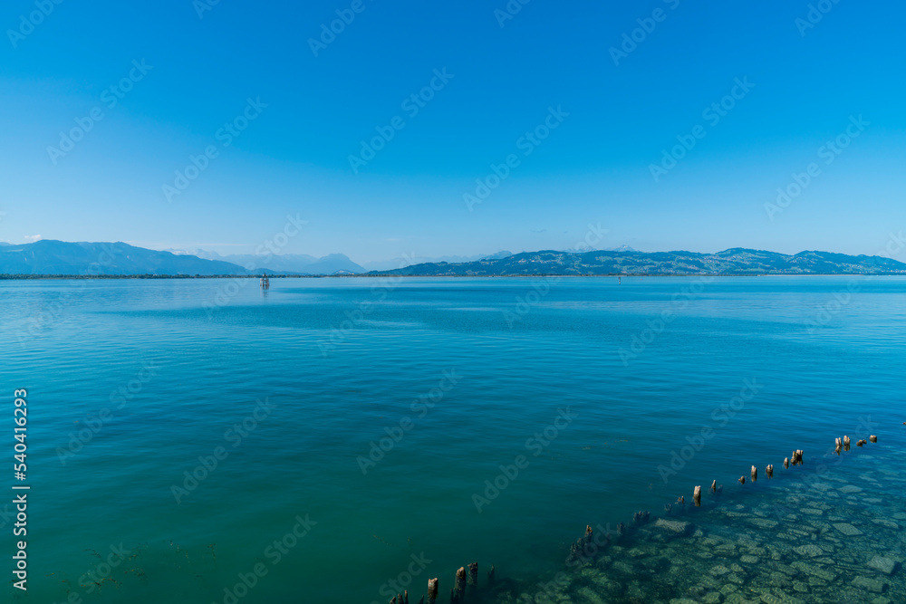 Germany, Bodensee lake view to austrian and swiss alps mountains coast beautiful clear water of lake constance with blue sky in summer