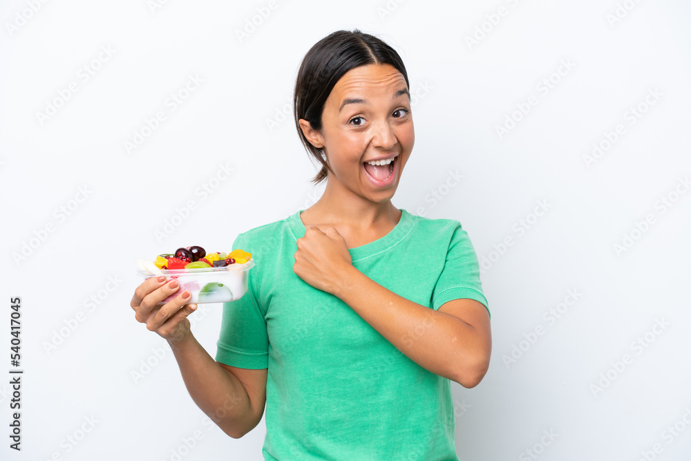 Young hispanic woman holding a bowl of fruit isolated on white background celebrating a victory Young hispanic woman holding a bowl of fruit isolated on white background celebrating a victory