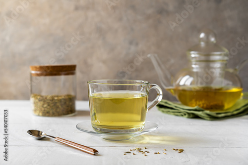 Tableau sur toile Fennel tea in a glass cup, fennel seeds in a jar, tea pot on white wooden table