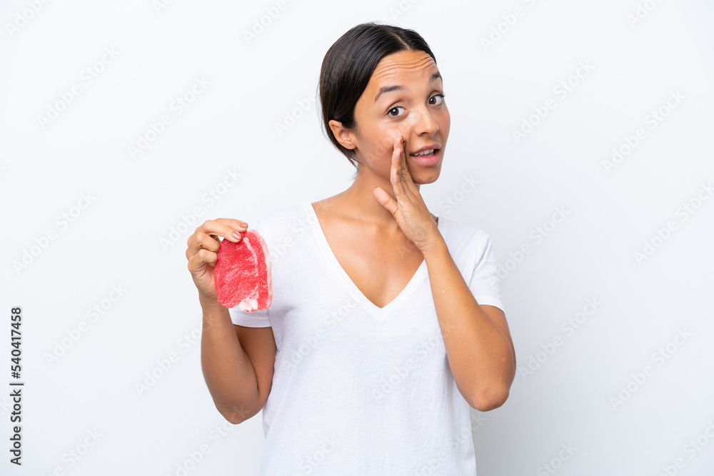 Young hispanic woman holding a piece of meat isolated on white background whispering something Young hispanic woman holding a piece of meat isolated on white background whispering something