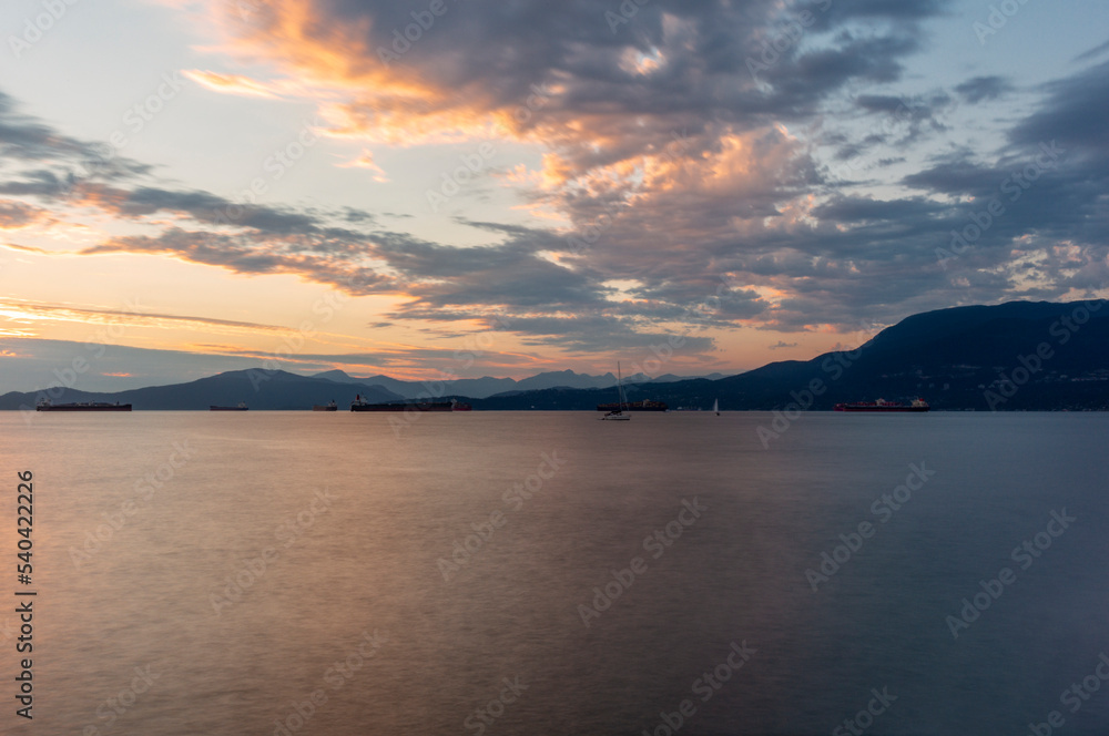 Sunset on the sea in front of Vancouver with container ships, sail boat and stand-up paddles Sunset on the sea in front of Vancouver with container ships, sail boat and stand-up paddles