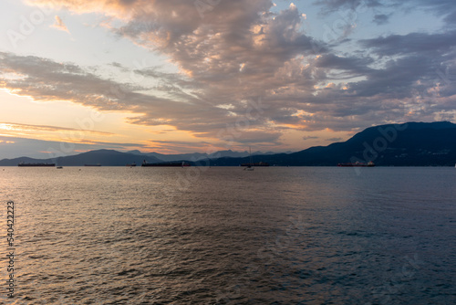 Sunset on the sea in front of Vancouver with container ships  sail boat and stand-up paddles