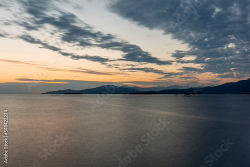 Sunset on the sea in front of Vancouver with container ships  sail boat and stand-up paddles