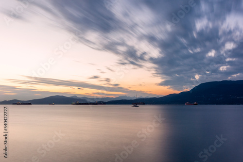 Sunset on the sea in front of Vancouver with container ships, sail boat and stand-up paddles