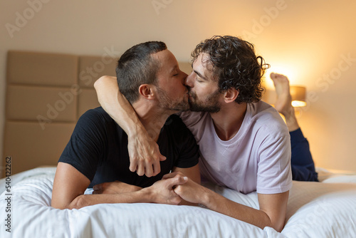 Two young man lgbtq gay couple dating in love hugging enjoying intimate tender sensual moment together kissing with eyes closed