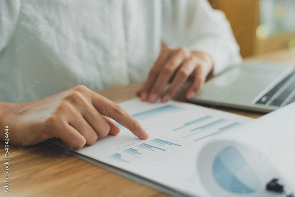 Professional businesswoman working on documents report show chart and graph with computer laptop at corporate office. Hands pointing white paperwork. Planing marketing, statistic analysis, concept Professional businesswoman working on documents report show chart and graph with computer laptop at corporate office. Hands pointing white paperwork. Planing marketing, statistic analysis, concept