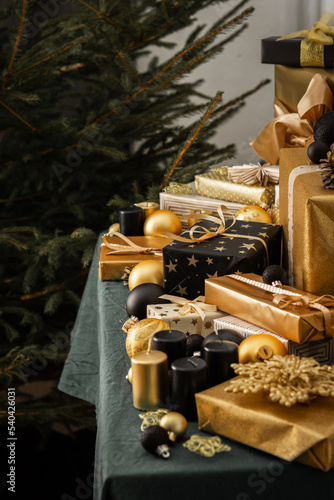Preparations for the holiday, for dressing the Christmas tree, black and gold gifts and Christmas toys and decorations on the table near the fir tree