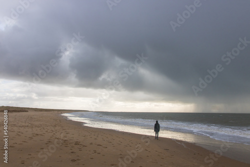 silhouette d'un jeune homme sur la plage sous un ciel orageux photo