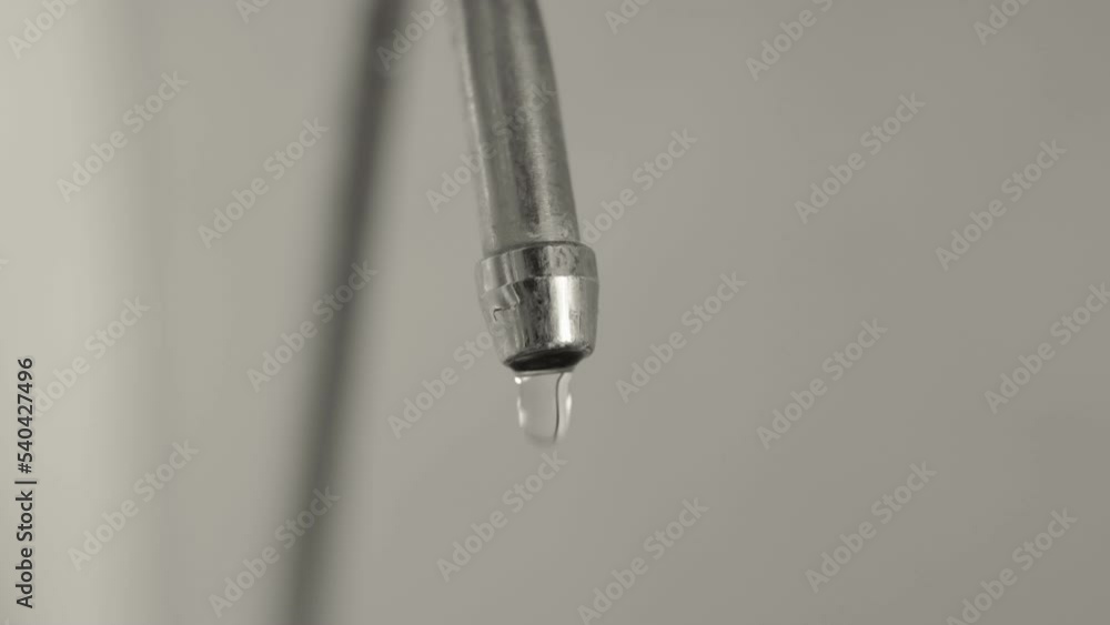 Macro, drops of clean drinking water dripping from a metal kitchen faucet, leaking a strategically important resource of the planet Macro, drops of clean drinking water dripping from a metal kitchen faucet, leaking a strategically important resource of the planet