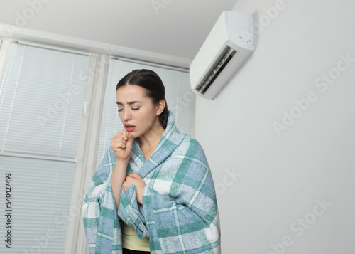Bilde på lerret Woman suffering from cold in room with air conditioner on white wall