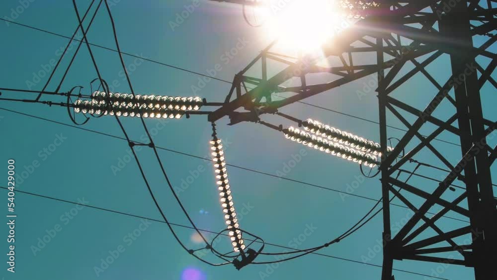 Power lines with sun rays on blue sky. High voltage substation ...