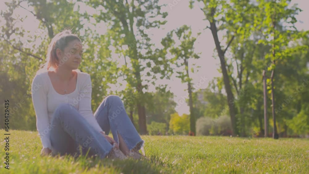 Beautiful girl sitting on a meadow in the park. Stretching smiling and leaning. Beautiful girl sitting on a meadow in the park. Stretching smiling and leaning.