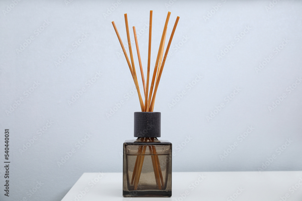 Aromatic reed freshener on table near white wall Aromatic reed freshener on table near white wall