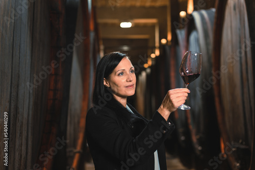 Фототапет Woman in the wine cellar with barrels in background drinking and tasting wine