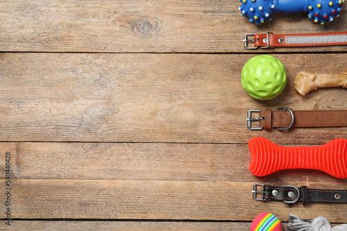 Flat lay composition with dog collars and toys on wooden table. Space for text