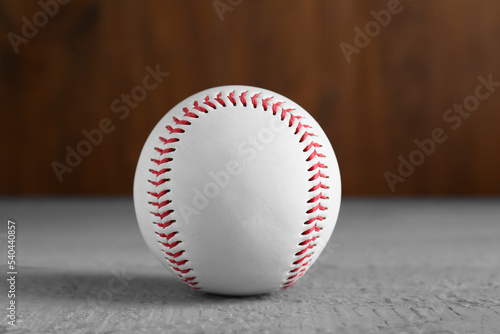 Baseball ball on grey wooden table, closeup. Sportive equipment