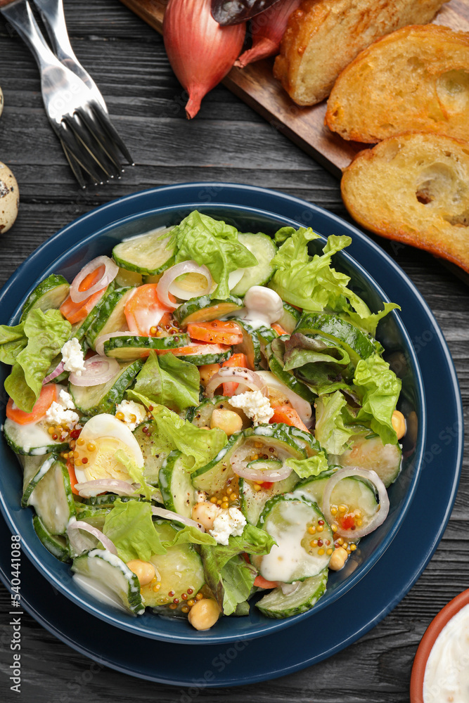Bowl of delicious cucumber salad served on black wooden table, flat lay Bowl of delicious cucumber salad served on black wooden table, flat lay