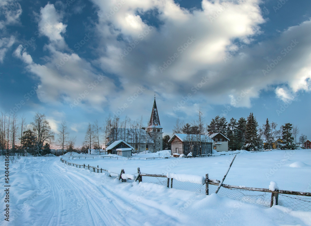 Fototapeta premium Wooden fence and old stone church on a winter day