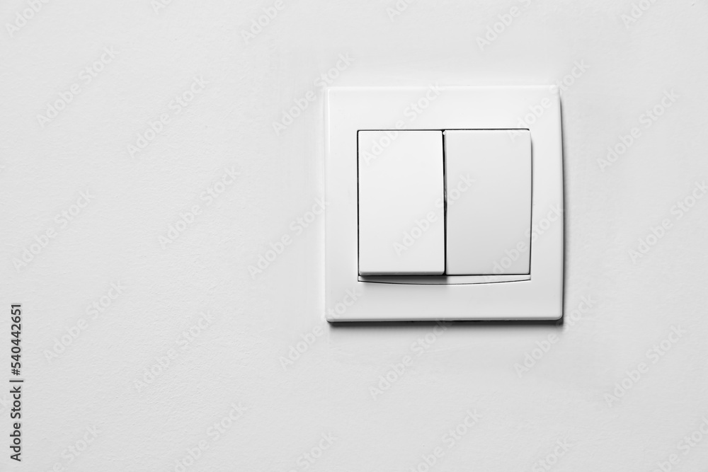 Modern plastic light switch on white wall, space for text Modern plastic light switch on white wall, space for text