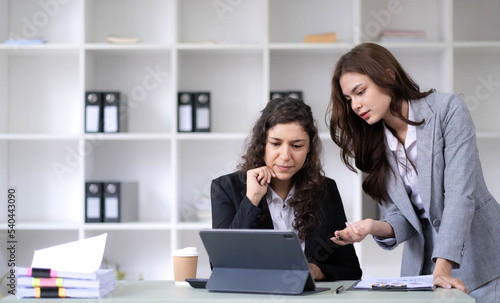 Two young Asian business woman talk, consult, discuss working with new startup project idea presentation analyze plan marketing and investment in the office.