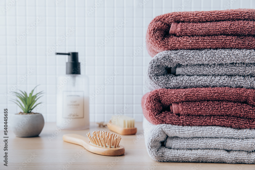 Towels. Clean fresh fluffy towels and bath accessories on table in bathroom  Stock Photo