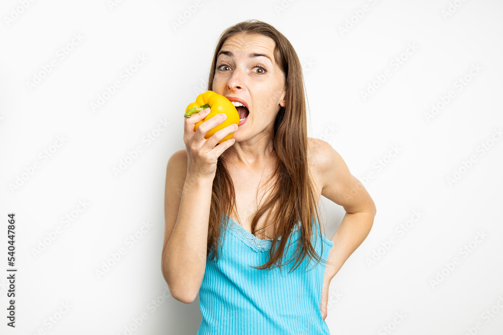 Young woman biting whole fresh yellow paprika on white background Young woman biting whole fresh yellow paprika on white background