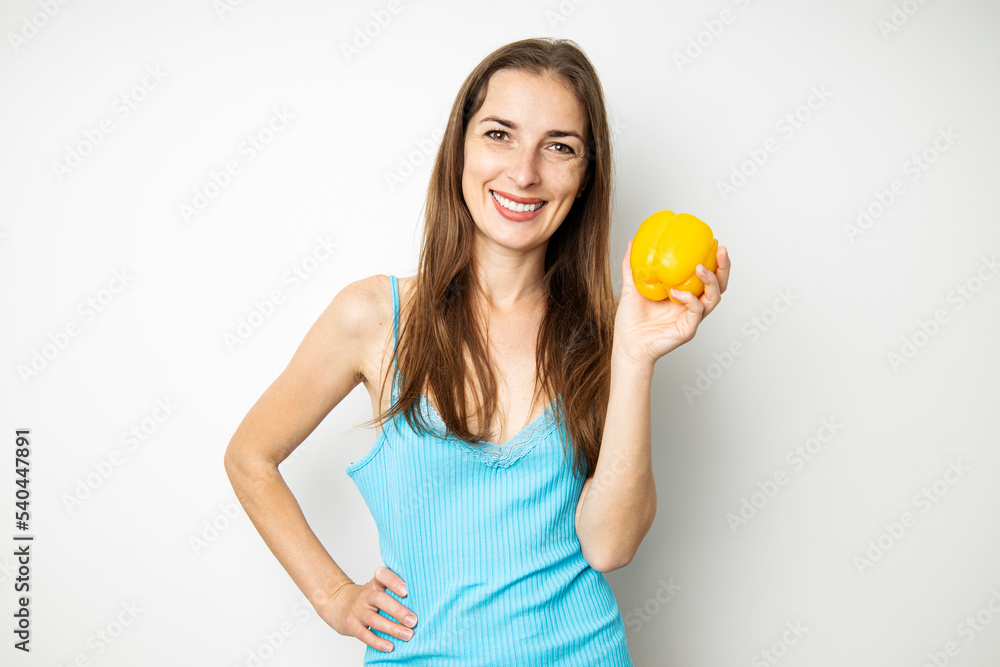 Smiling young woman holding yellow paprika on white background Smiling young woman holding yellow paprika on white background
