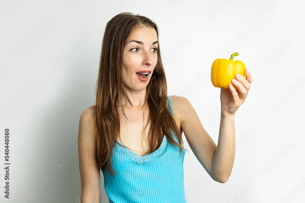 Young woman looking in surprise at yellow paprika isolated on white background Young woman looking in surprise at yellow paprika isolated on white background