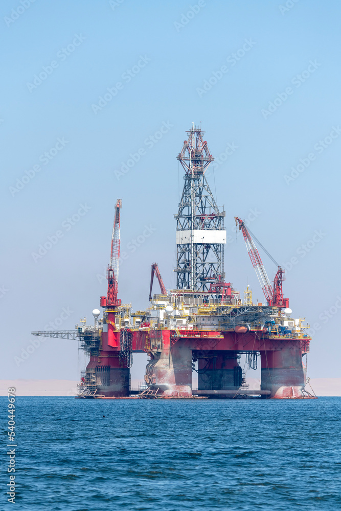 Photo of the oil derrick placed in the blue ocean water.