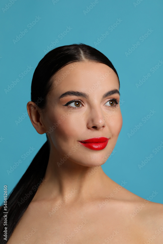 Fototapeta premium Attractive smiling woman against light blue background