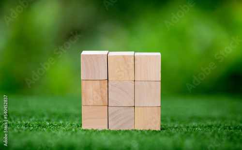 Stacking blank wooden cubes on green background with copy space for input wording and infographic icon. Empty brown wooden object block for symbol icon put technology  zero gravity  business concept.