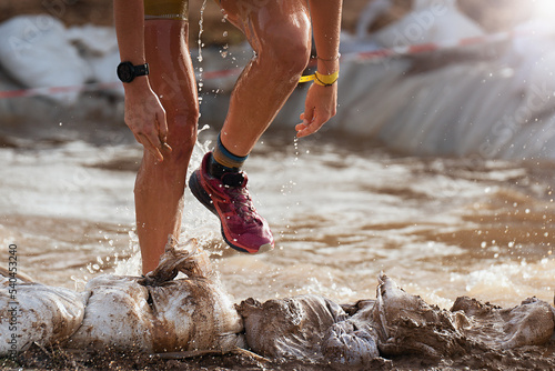 Participant in an obstacle course race runs out of a water obstacle, concept of hardness and effort