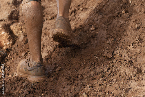 Mud race runner very muddy running shoes, muddy feet detail