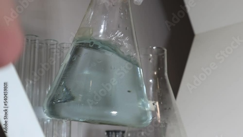 Hydrochloric acid in a flask. The girl checks whether hydrochloric acid has reacted. Videos chemicals concept photo