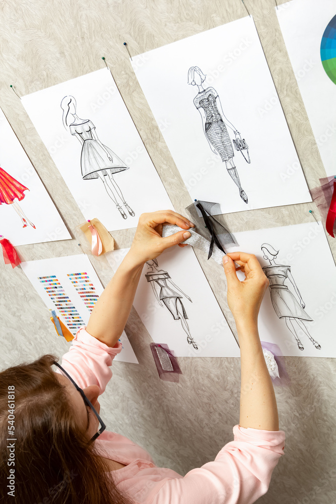 Woman fashion designer is working on creating sketches of dresses. Design and tailoring. Seamstress in the studio.